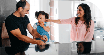 Parents with their young child in the kitchen, all smiling and interacting