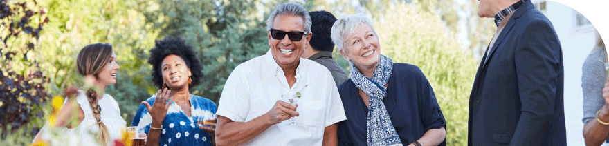 Group of people enjoying an outdoor gathering, with a man in sunglasses and a woman smiling in the foreground