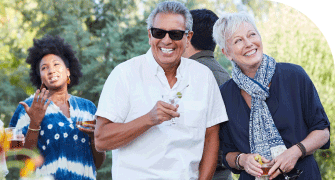 Group of people enjoying an outdoor gathering, with a man in sunglasses and a woman smiling in the foreground