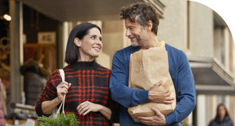 A couple smiling and walking with shopping bags outside a clothing store