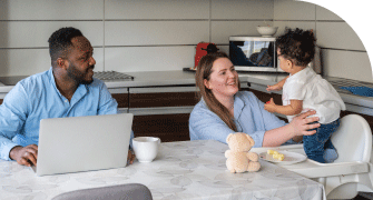 Parents sitting at a table with their young child in a modern kitchen, interacting and smiling
